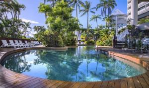 Una piscina en un resort con sillas y palmeras. en Luxury waterfront sea view apartment - do not book, en Cairns