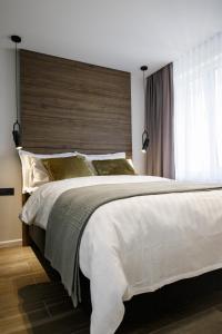 a bedroom with a large white bed with a wooden headboard at City Center Apartment in Siauliai in Šiauliai