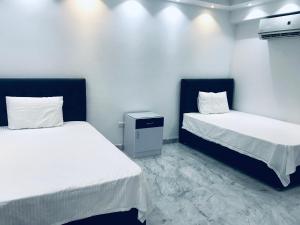 Dos camas en una habitación con paredes blancas. en Shehab Saraya, en El Cairo