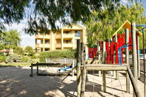 
a playground with wooden benches and a fence at Abbey Beach Resort in Busselton
