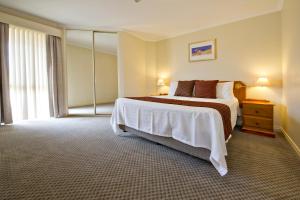 
a bedroom with a bed and a dresser at Abbey Beach Resort in Busselton
