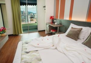 a bedroom with a bed with white sheets and a window at HelicoNia Hotel in George Town