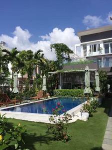 ein Pool mit Sonnenschirmen und ein Haus in der Unterkunft Riverside Villa Homestay in Đà Nẵng