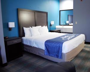 a bedroom with a large bed with a blue wall at Days Inn by Wyndham Montgomery in Montgomery