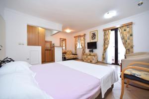 a bedroom with a white bed and a living room at Bologna Apartments in Budva