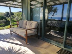 a couch on a porch with a view of the ocean at Okari Cottage in Cape Foulwind