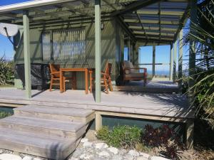 Cape Foulwind的住宿－Okari Cottage，海滩上带桌椅的凉亭