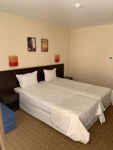 1 dormitorio con 1 cama blanca grande y 2 almohadas en Tropics Hotel - Ultra All Inclusive, en Sveti Vlas