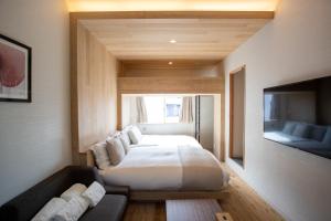 a bedroom with a bed and a couch and a tv at Sakura Cross Hotel Shinjuku East in Tokyo