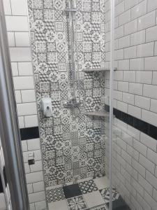 a shower with a glass door with a mosaic tile wall at Vila Yly in Eforie Nord