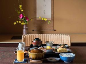 松山市にある道後温泉 大和屋別荘 の食べ物とオレンジジュースのトレイ付きテーブル