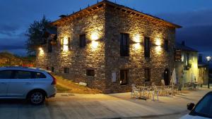 a car parked in front of a stone building with lights at La Posada del Druida in Foncebadón