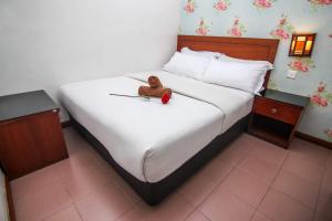 a bed with a teddy bear sitting on top of it at Rose Cottage Hotel Taman Daya in Johor Bahru +1 photo