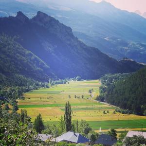 einen Blick auf ein großes Feld mit Bergen im Hintergrund in der Unterkunft Le balcon fleuri in Freissinieres