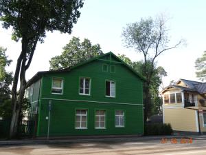 a green house in front of a house at JURMALA APARTMENT in Jūrmala