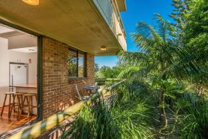 a balcony of a house with a palm tree at Breeze@Byron 1 Clarkes Beach in Byron Bay
