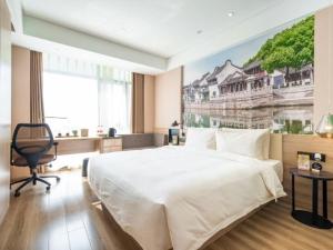 a bedroom with a large bed with a painting on the wall at Atour Hotel Suzhou Industrial Park Qingjian Lake Branch in Suzhou