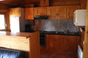 uma cozinha com armários de madeira e um forno com placa de fogão em Chalet Dennerust - The Original em Durbuy