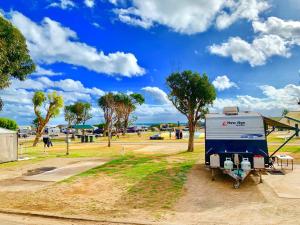 Sunset Beach Holiday Park في جيرالدتون: مقطورة زرقاء وبيضاء متوقفة في الحديقة