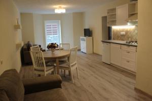 a living room with a table and chairs and a kitchen at Apartamentai Vanagupės rajone in Palanga