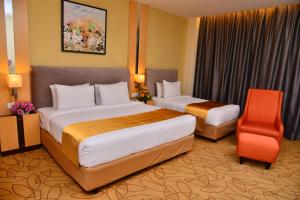 um quarto de hotel com duas camas e uma cadeira em Metro Hotel Bukit Bintang em Kuala Lumpur
