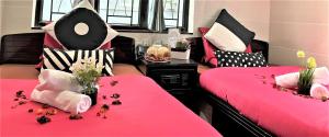 a room with two beds with pink sheets and flowers at Cebu Inn in Hong Kong