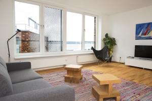 ein Wohnzimmer mit einem Sofa, Tischen und Fenstern in der Unterkunft Ferienwohnung Fjordblick in Flensburg, Sonwik in Flensburg