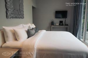 a bedroom with a white bed with pillows and a tv at The Hidden Resort in Ranong