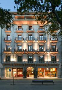 um edifício com varandas e um banco em frente em Acta Atrium Palace em Barcelona