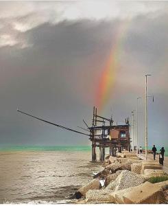 a rainbow over a beach with a pier and the ocean at Case vacanze I trabocchi in San Vito Chietino