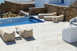 a patio with chairs and a swimming pool at Mykonos Panormos Villas in Mykonos