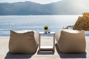 two chairs and a table with a view of the water at Mykonos Panormos Villas in Mykonos