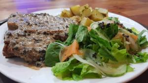 a plate of food with meat and salad on a table at Hotel Gabriella in Tagbilaran City