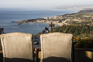 een tafel en stoelen met uitzicht op de oceaan bij Hotel Villa Ducale in Taormina