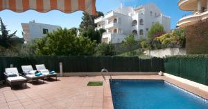 a swimming pool with two chairs and a building at Apartament Les Tonyines in Llança