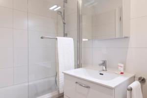 a white bathroom with a sink and a shower at Nest - Badenerstrasse 356 in Zürich