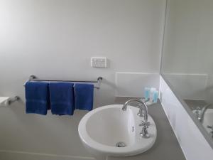 a white bathroom with a sink and blue towels at Horrocks Beach Caravan Park in Horrocks