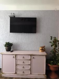 une télévision sur un mur au-dessus d'une commode blanche dans l'établissement P. Stradiņa iela 17 Апартаменты, à Ventspils