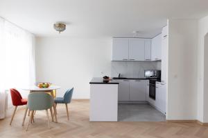 a kitchen with white cabinets and a table and chairs at Nest - Badenerstrasse 356 in Zürich
