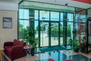 a lobby with a red chair and glass walls at Ellinis Hotel in Varna City