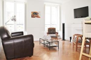 una sala de estar con un sofá de cuero negro y sillas en L'Appart D'Oli et Tiane, en Burdeos
