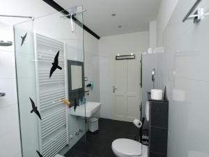 ein Badezimmer mit einem WC und einer Dusche mit Vögeln an der Wand in der Unterkunft Küstenwilla FeWo Usedom in Zinnowitz