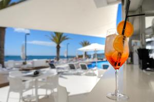 a drink with an orange on a table next to a beach at Apartamentos Vibra Jabeque Dreams in Ibiza Town