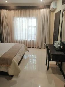 - une chambre avec un lit, un bureau et une fenêtre dans l'établissement Erasmia Palms Boutique Hotel & Spa, à Centurion