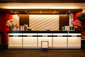 a lobby with a counter with a stool in front at Sejour Inn Capsule in Hiroshima