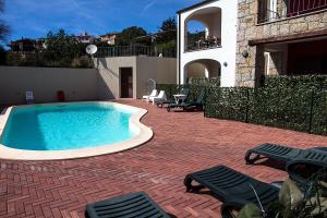 a swimming pool with chairs and a house at GF Apartments La Vigna in Badesi