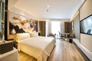 Habitación de hotel con cama grande y TV en Atour Hotel Phoenix Avenue Shangrao, en Shangrao