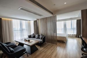 een woonkamer met een bank, een bed en een tafel bij Atour Hotel Phoenix Avenue Shangrao in Shangrao