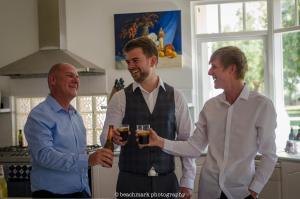3 Männer stehen in einer Küche mit Biergläsern in der Unterkunft Fairlawn Estate in Busselton
