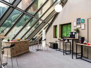 Habitación grande con ventanas, mesas y taburetes. en ibis Paris Alesia Montparnasse, en París